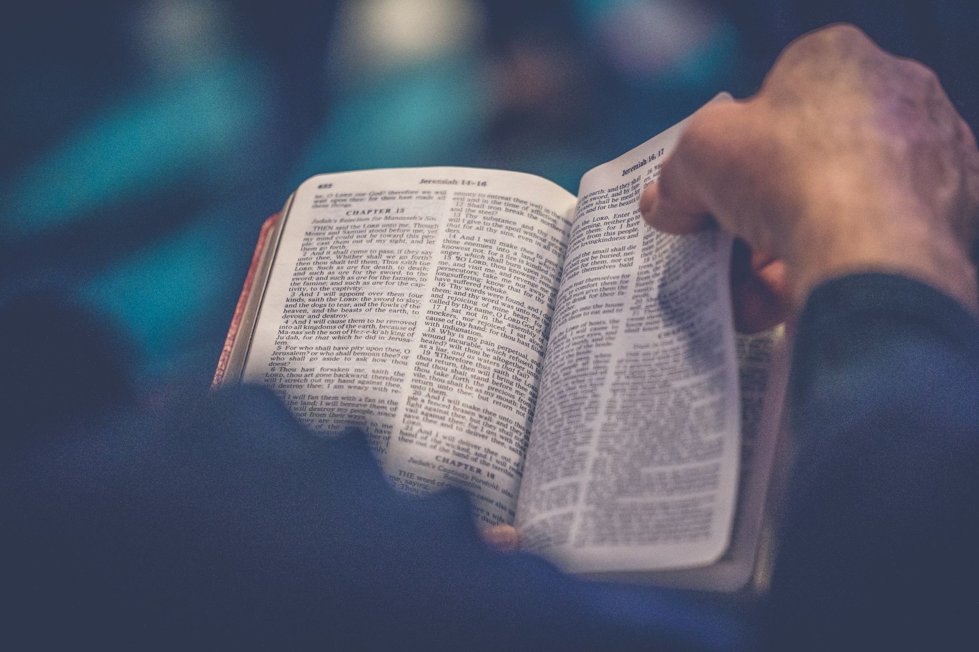 A hand turning the page of an open Bible